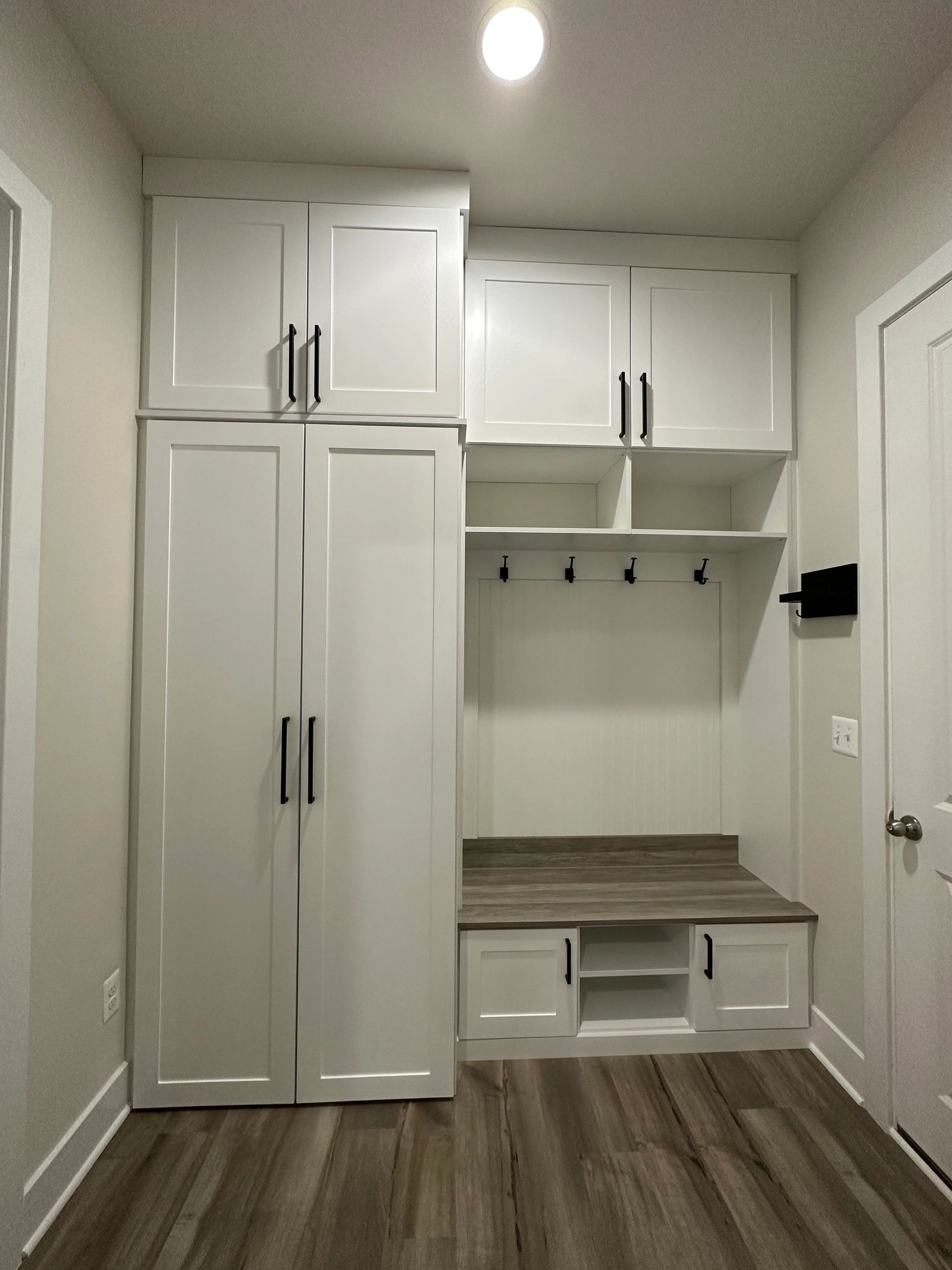 Custom mudroom white cabinetry black handles wood countertop Fantasy Closets